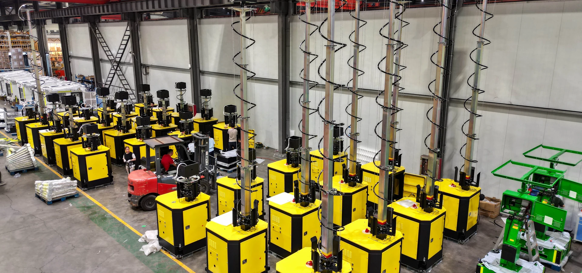 Yellow mast equipment arranged inside the workshop shown in the supplied photographs