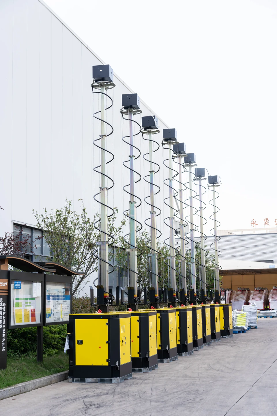 A row of yellow mast equipment photographed outdoors beside a building
